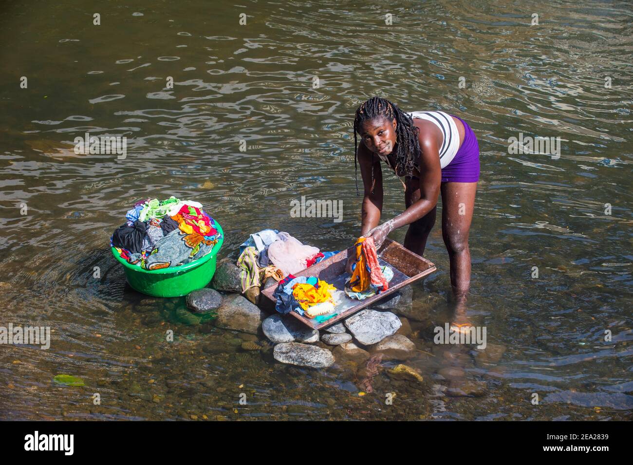 Donna lavando i suoi vestiti in un fiume alla costa orientale di Sao Tomé, Sao Tomé e Principe, Oceano Atlantico Foto Stock
