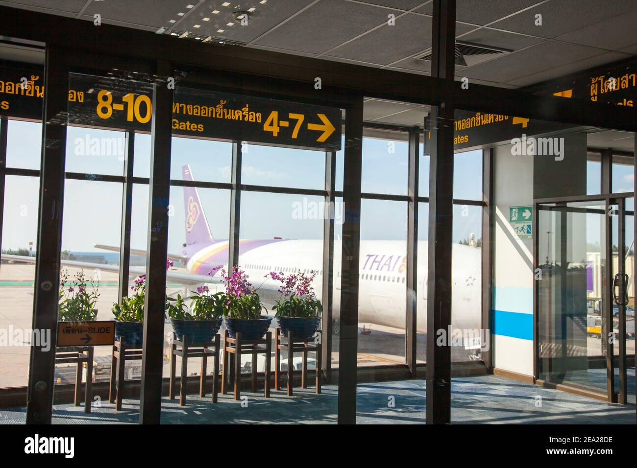 Aeroporto Internazionale di Phuket in Thailandia. Vista dal cancello. In primo piano c'è una finestra dietro la quale, in un aereo alato, una compagnia aerea thailandese e. Foto Stock