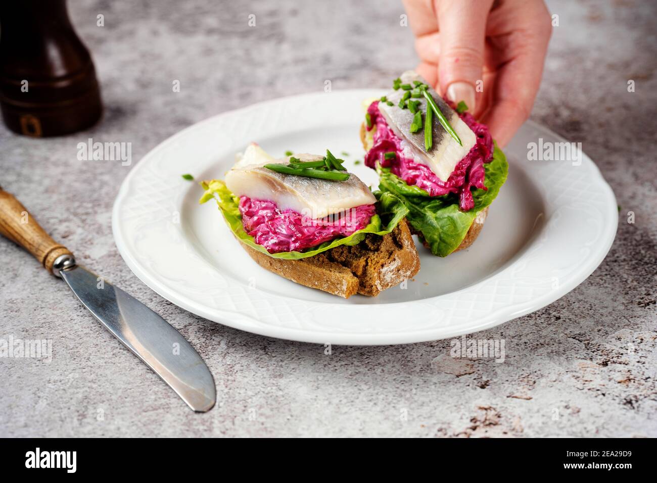 Panino femminile per la presa a mano con aringhe dal piatto Foto Stock