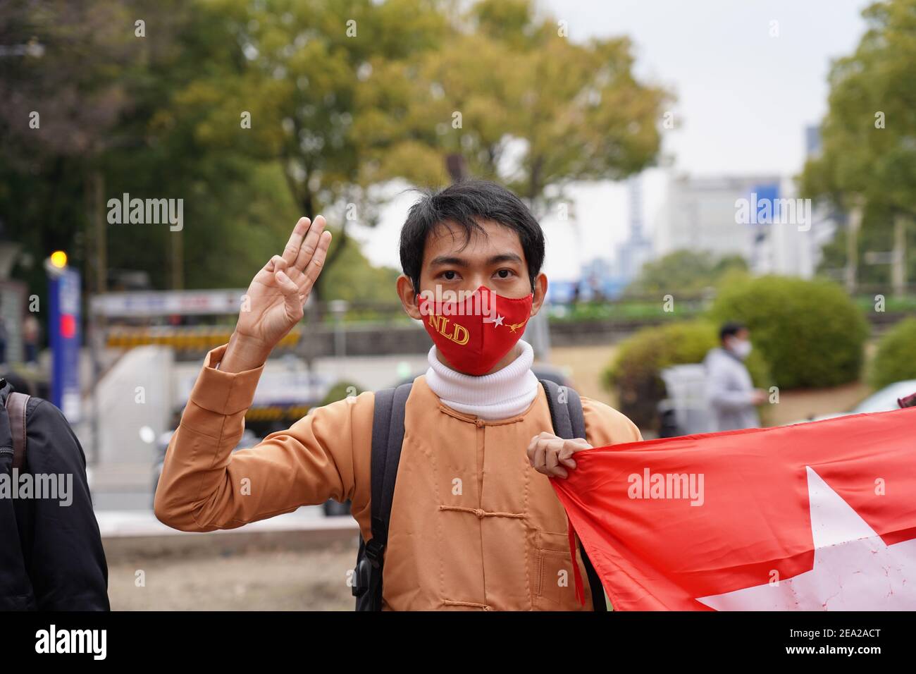 Un manifestante che indossa una maschera facciale e tiene una bandiera solleva un saluto a tre dita durante una protesta contro un colpo di stato militare nel loro paese.centinaia di residenti in Myanmar in Giappone scesi per le strade in una protesta che chiede il rilascio del leader della Lega nazionale per la democrazia (NLD) Aung San Suu Kyi e. altri politici detenuti dai militari. Foto Stock