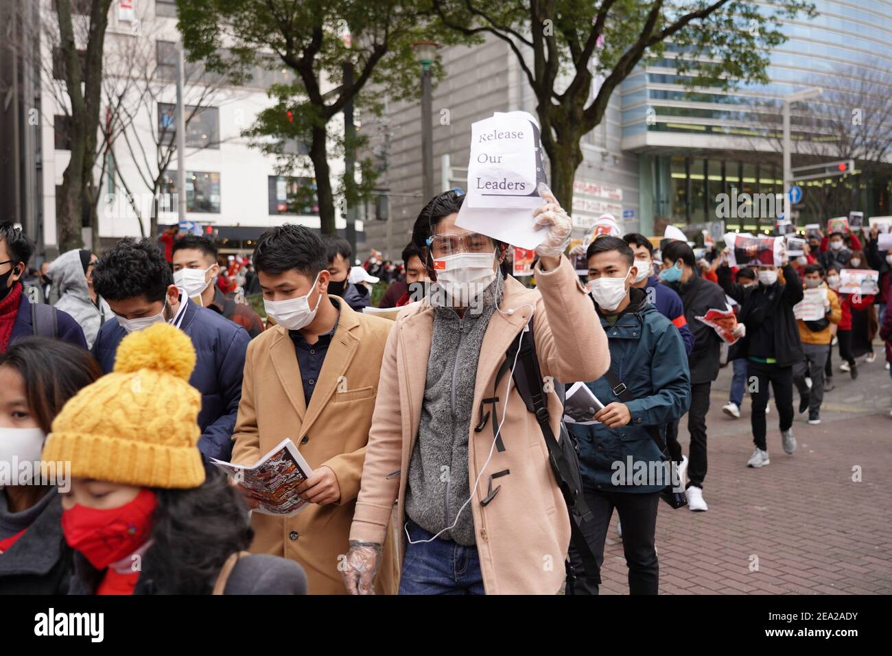 I manifestanti che indossano mascherine portano dei cartelli durante una protesta contro un colpo di stato militare nel loro paese. Centinaia di abitanti del Myanmar in Giappone scapparono in piazza con una protesta che chiedeva il rilascio del leader della Lega nazionale per la democrazia (NLD) Aung San Suu Kyi e di altri politici detenuti dai militari. Foto Stock