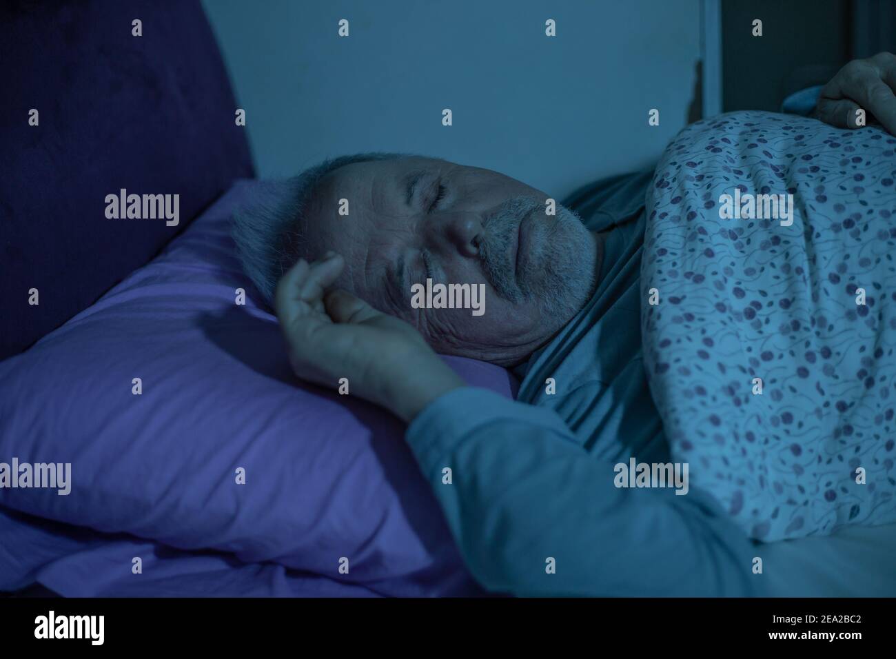 L'uomo anziano si addormenta nel letto durante la mezzanotte Foto Stock