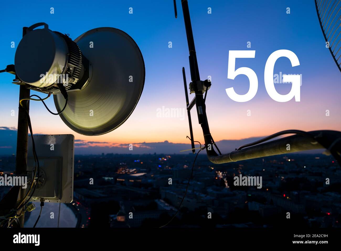 Il primo piano della torre delle comunicazioni cellulari è sullo sfondo della città serale al tramonto. Aggiunto testo 5G. Reti 5G Concept . Foto Stock