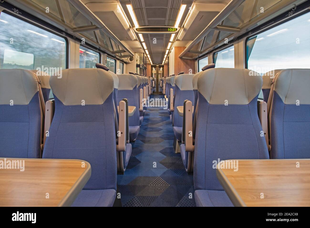 Vista dell'interno di una carrozza vuota deserta per pendolari con file di sedili e tavoli Foto Stock
