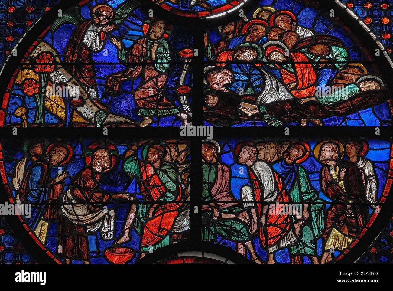 L'agonia a Getsemani (in alto) e Gesù lavando i piedi dei suoi discepoli nell'ultima cena: Due scene della settimana Santa Passione di Cristo raffigurato in un roundel di vivide vetrate del 13th ° secolo nella finestra lancetta centrale che piercing la parete del coro orientale del medievale gotico Cathédrale Notre-Dame de Laon a Laon, Aisne, Hauts-de-France, Francia. La scena superiore mostra gli apostoli stanchi che dormono nel Giardino del Getsemani, nonostante promettano che Gesù avrebbe vegliato e pregato mentre sopportava l'angoscia di sapere che sarebbe stato tradito, arrestato e crocifisso. Foto Stock