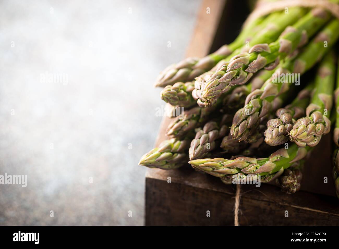 Mazzo di spighe di asparagi verdi fresche in una scatola su sfondo rustico Foto Stock