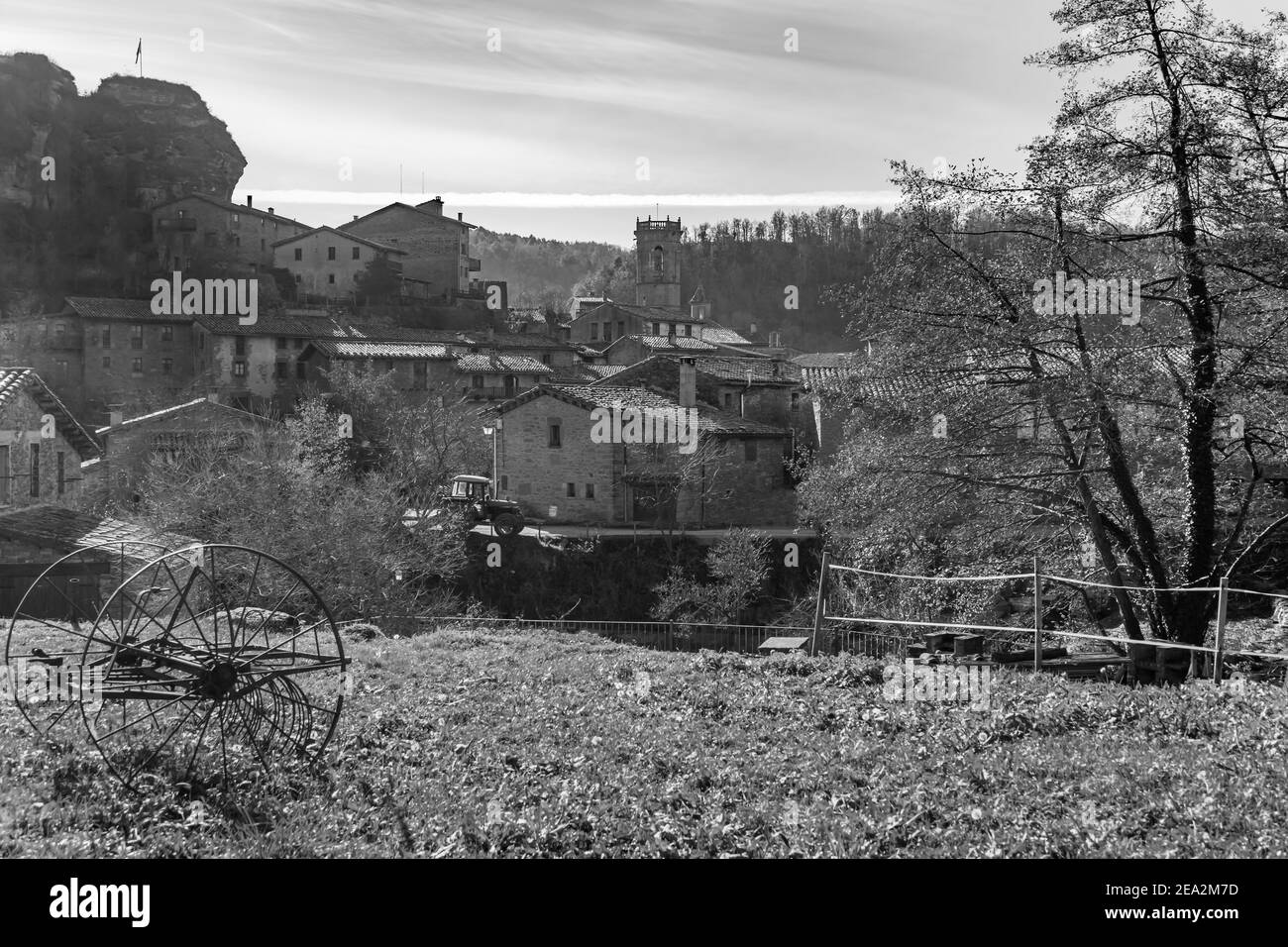 Splendida vista dell'antico borgo medievale di Rupit da Un campo con vecchie ruote in ferro rimorchio e un trattore.in marcia Countryside Concept.Black e. Foto Stock
