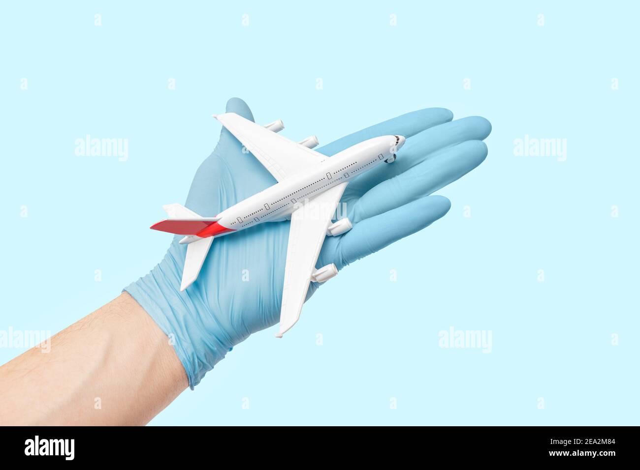 Il medico in guanti medici sta tenendo un aeroplano giocattolo. Concetto di restrizione di volo e quarantena. Assistenza umanitaria e situazione di emergenza Foto Stock