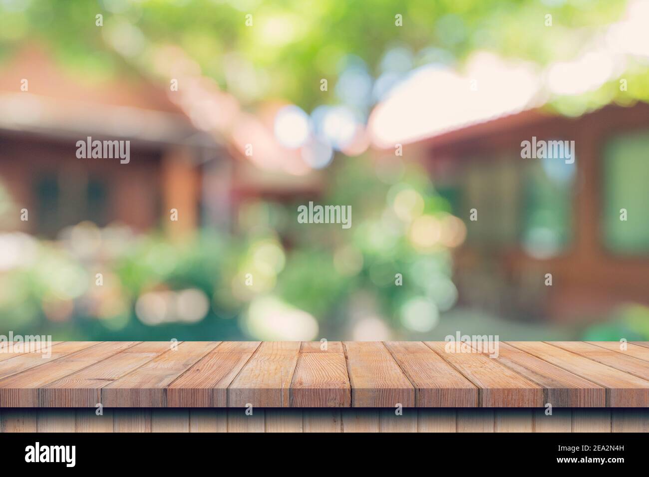 Tavolo vuoto in legno, bokeh sfocato e sfondo sfocato di alberi da giardino con luce solare. Modello di esposizione del prodotto. Foto Stock