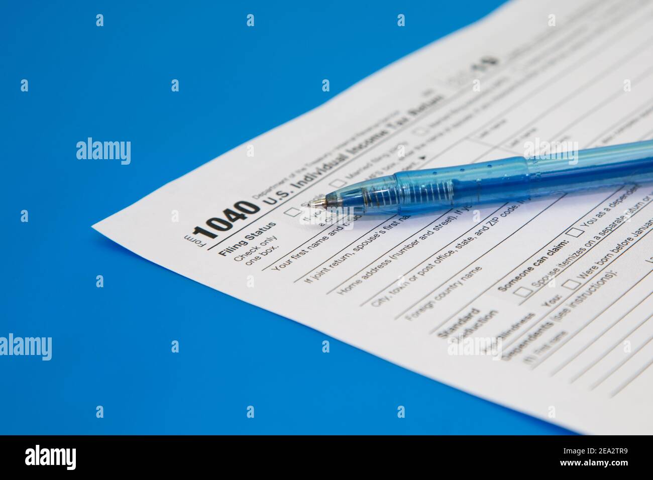 Chiusura della dichiarazione dei redditi su sfondo blu. Penna blu sul modulo fiscale 1040. Messa a fuoco selettiva Foto Stock