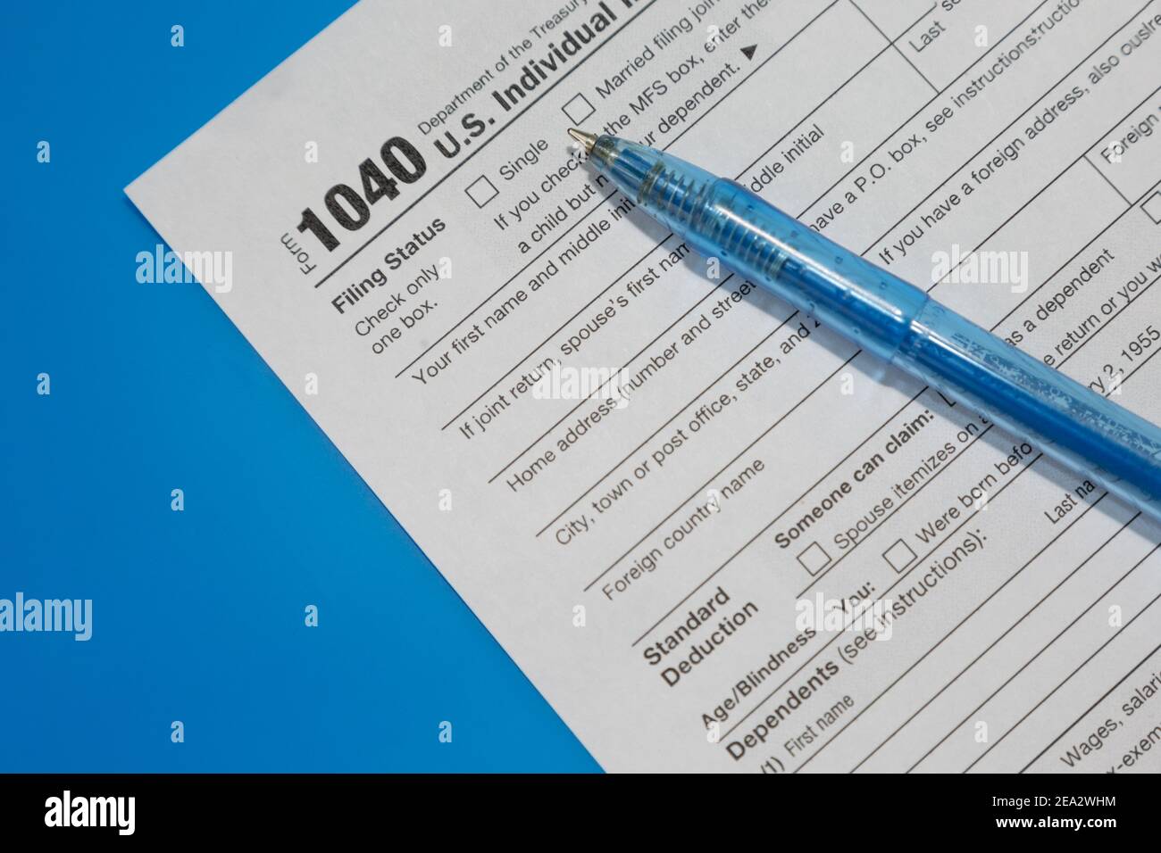 American Tax Form 1040 una penna si trova su uno sfondo blu della cartella. Foto Stock