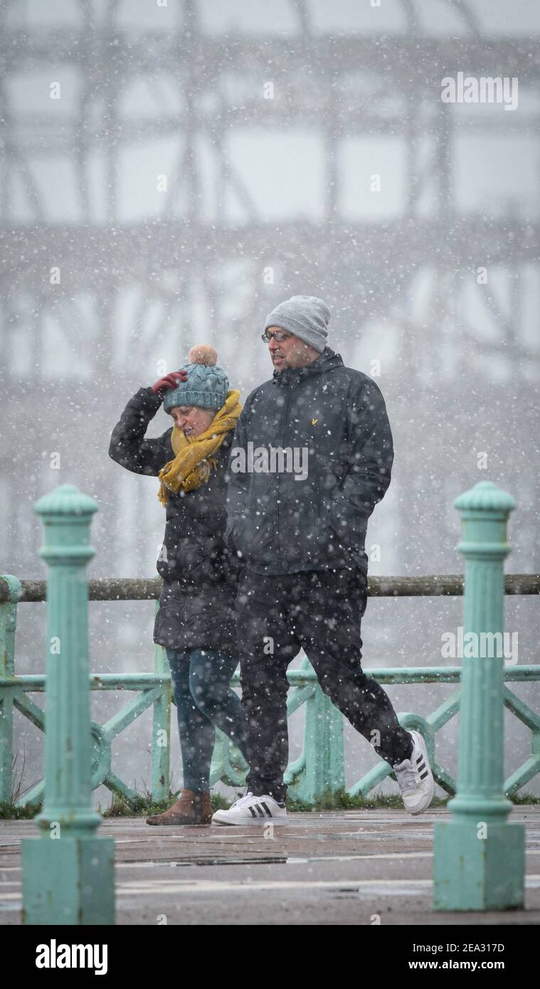 Due persone camminano lungo il lungomare vicino al West Pier di Brighton, domenica 9 febbraio 2021 Foto Stock