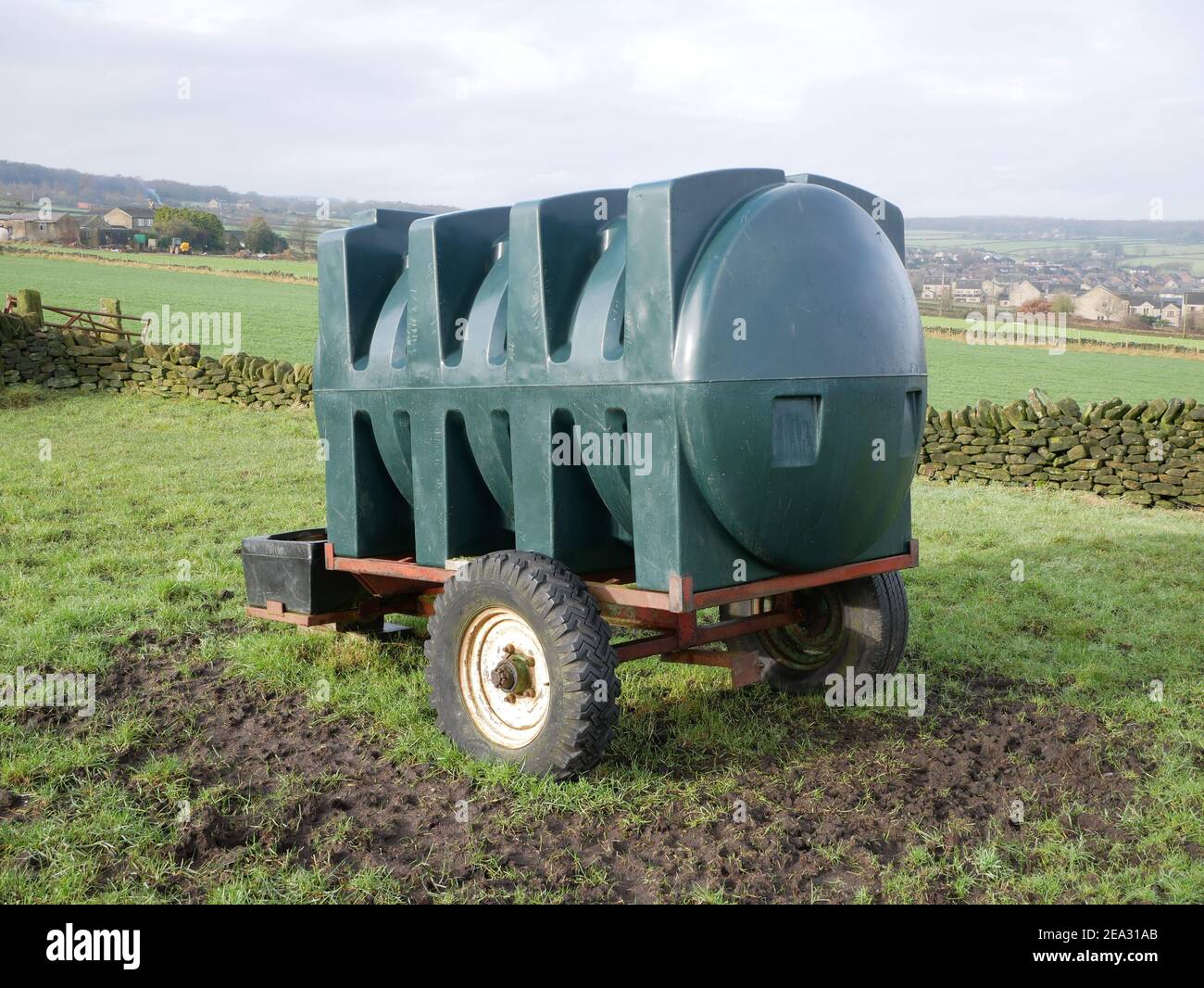 Grande serbatoio dell'acqua in plastica di forma verde su rimorchio a due ruote in campo agricolo Foto Stock