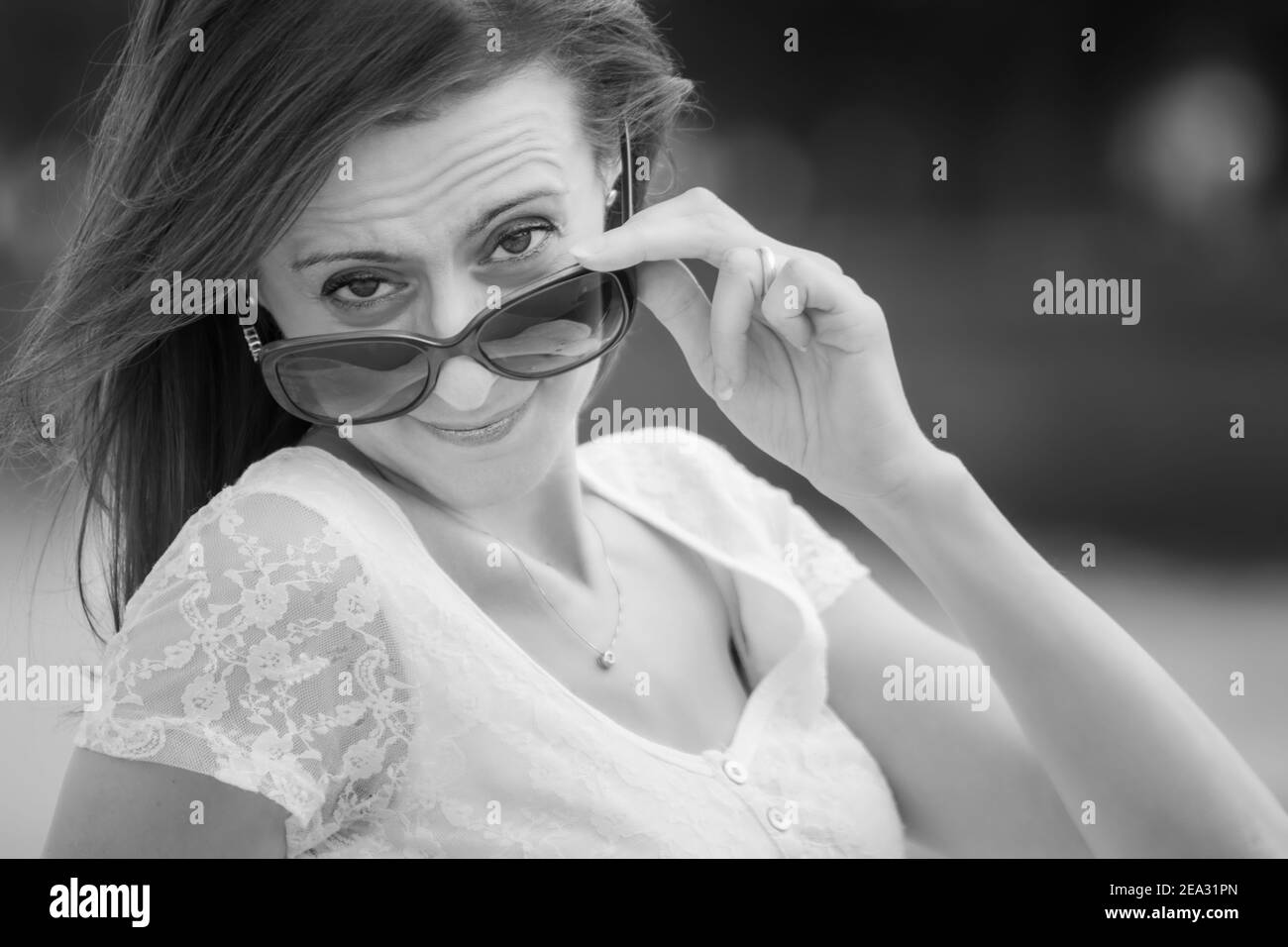 Ritratto in bianco e nero di giovane caucasica che guarda sopra i grandi occhiali da sole Foto Stock