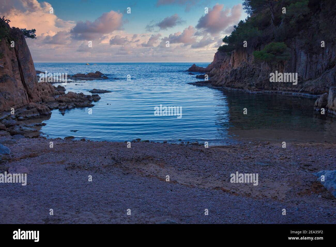 Vista di una delle piccole insenature della costa raggruppata di Aigua Xelida all'inizio dell'ora blu dove acquista colori blu e rosa. Costa Foto Stock