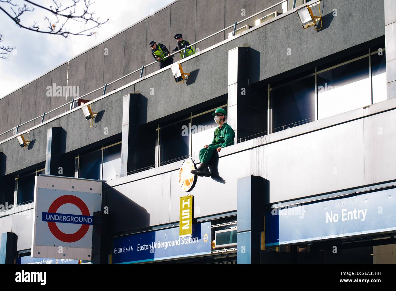 Un attivista maschile che tiene un cartello sale sul tetto di Euston Station, Londra UK in protesta contro il progetto HS2, 29 gennaio 2021. Foto Stock