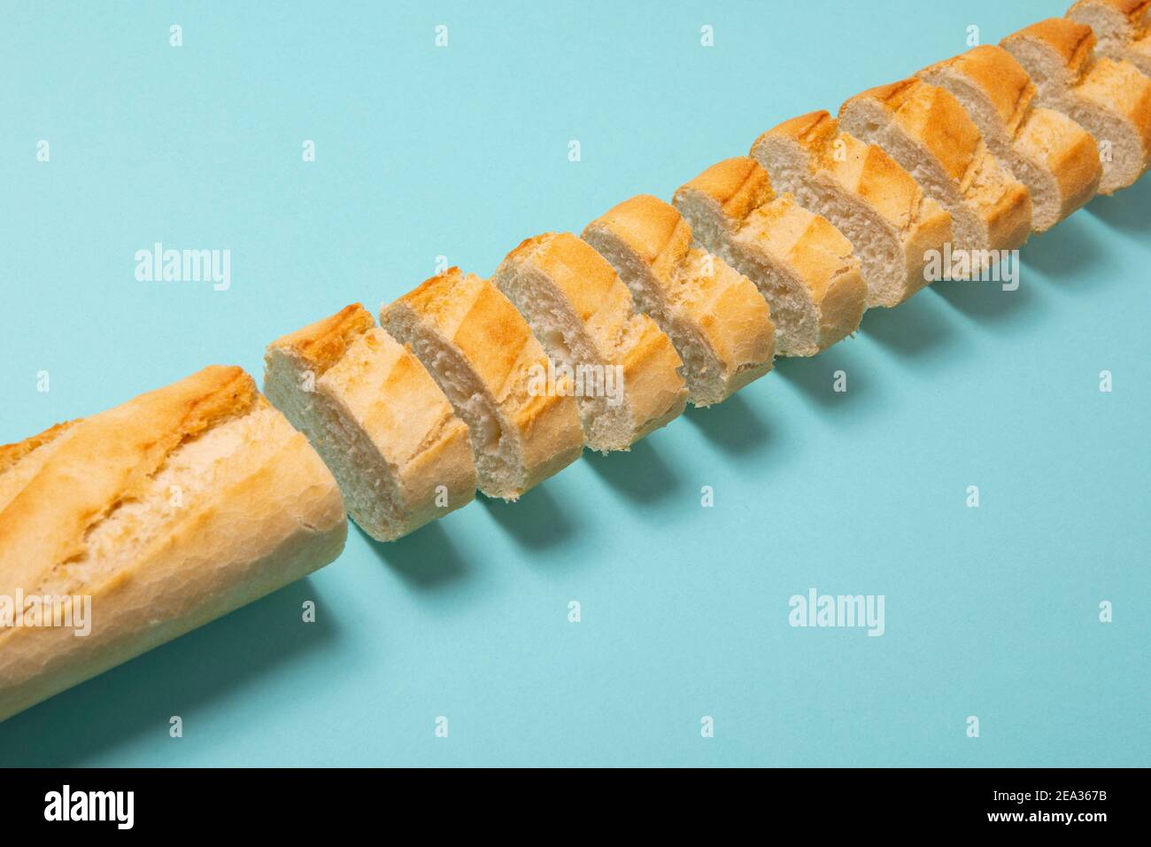 Baguette tagliata su sfondo blu. Concetto di pane semplice Foto Stock