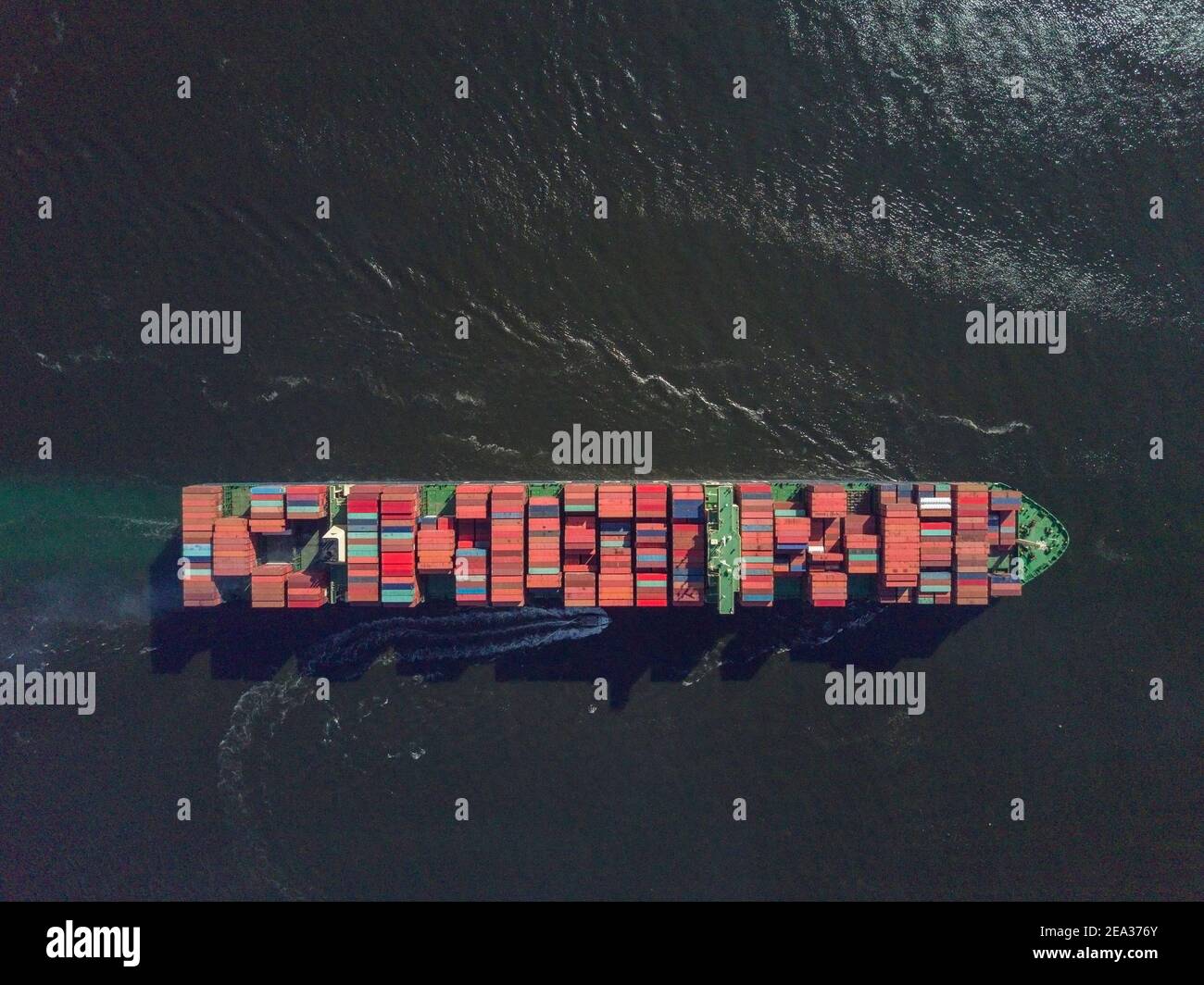 Vista aerea da un drone di una nave container, che trasporta container di grandi dimensioni attraverso una delle più trafficate rotte di navigazione dell'Asia - il canale di Lamma - tra Aberdeen sull'isola di Hong Kong e l'isola di Lamma. Il percorso è così affollato che ogni nave richiede una barca pilota da e per le banchine per navigare in questa parte del mare. © Olli Geibel Foto Stock