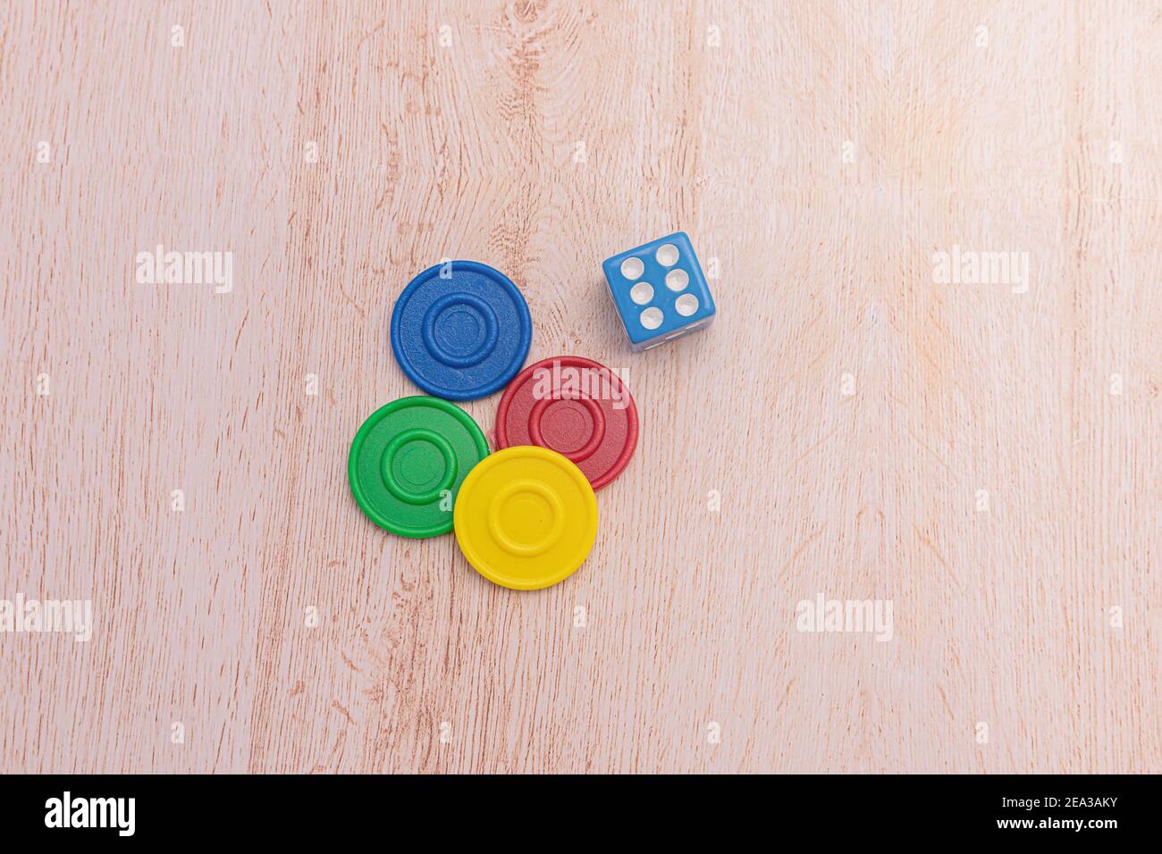 Chip di gioco colorati e un dado blu isolato su una superficie di legno. Concetto di giochi da tavolo e didattici. Il concetto di giochi da tavolo. Gioco da tavolo. Asse g Foto Stock