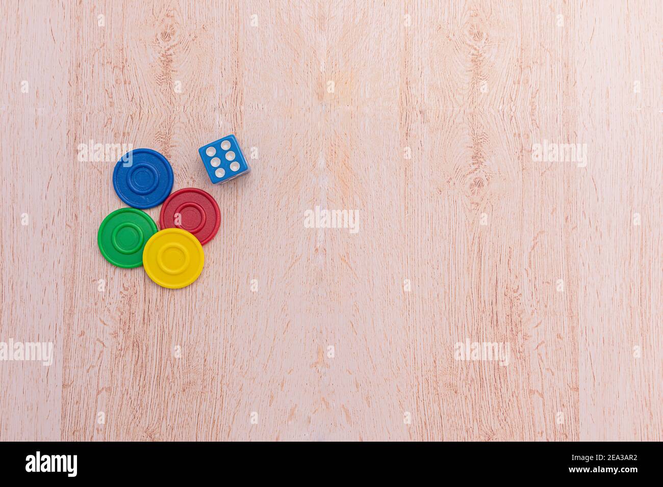 Chip di gioco colorati e un dado blu isolato su una superficie di legno. Concetto di giochi da tavolo e didattici. Il concetto di giochi da tavolo. Gioco da tavolo. Asse g Foto Stock