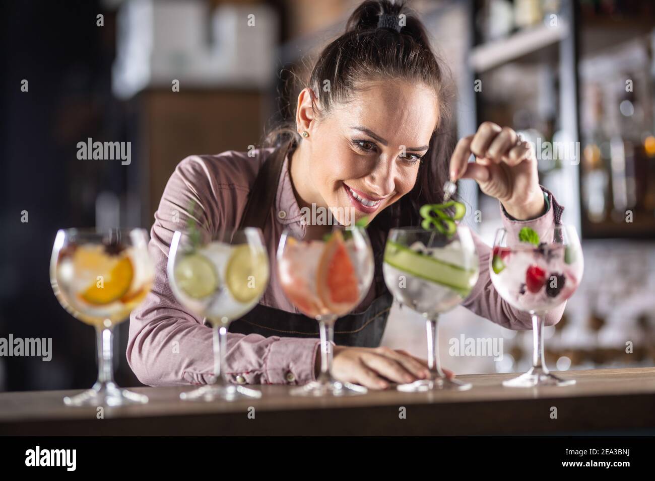 Ampia selezione di bevande toniche gin prodotte su un bar da un bel barman. Foto Stock