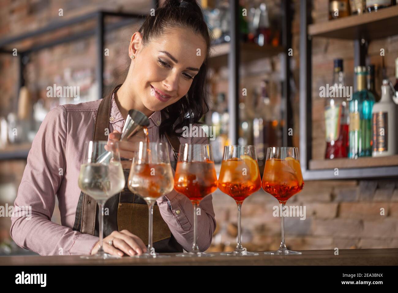 Happy barman trasforma in cinque bicchieri il cocktail aperol Spritz su un bar. Foto Stock