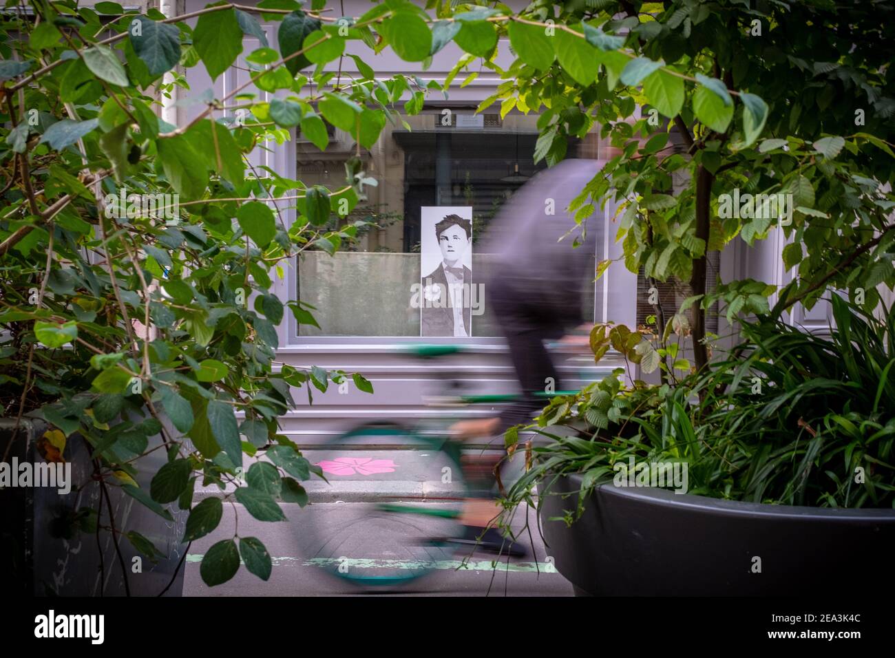 Il movimento offuscava l'uomo irriconoscibile che passava davanti a una finestra In cui c'è l'immagine del poeta Rimbaud in Parigi Foto Stock