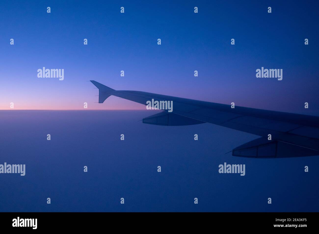L'ala sinistra di un grande aereo commerciale bianco che sorvola l'Oceano Atlantico sotto il sole del mattino. Foto Stock