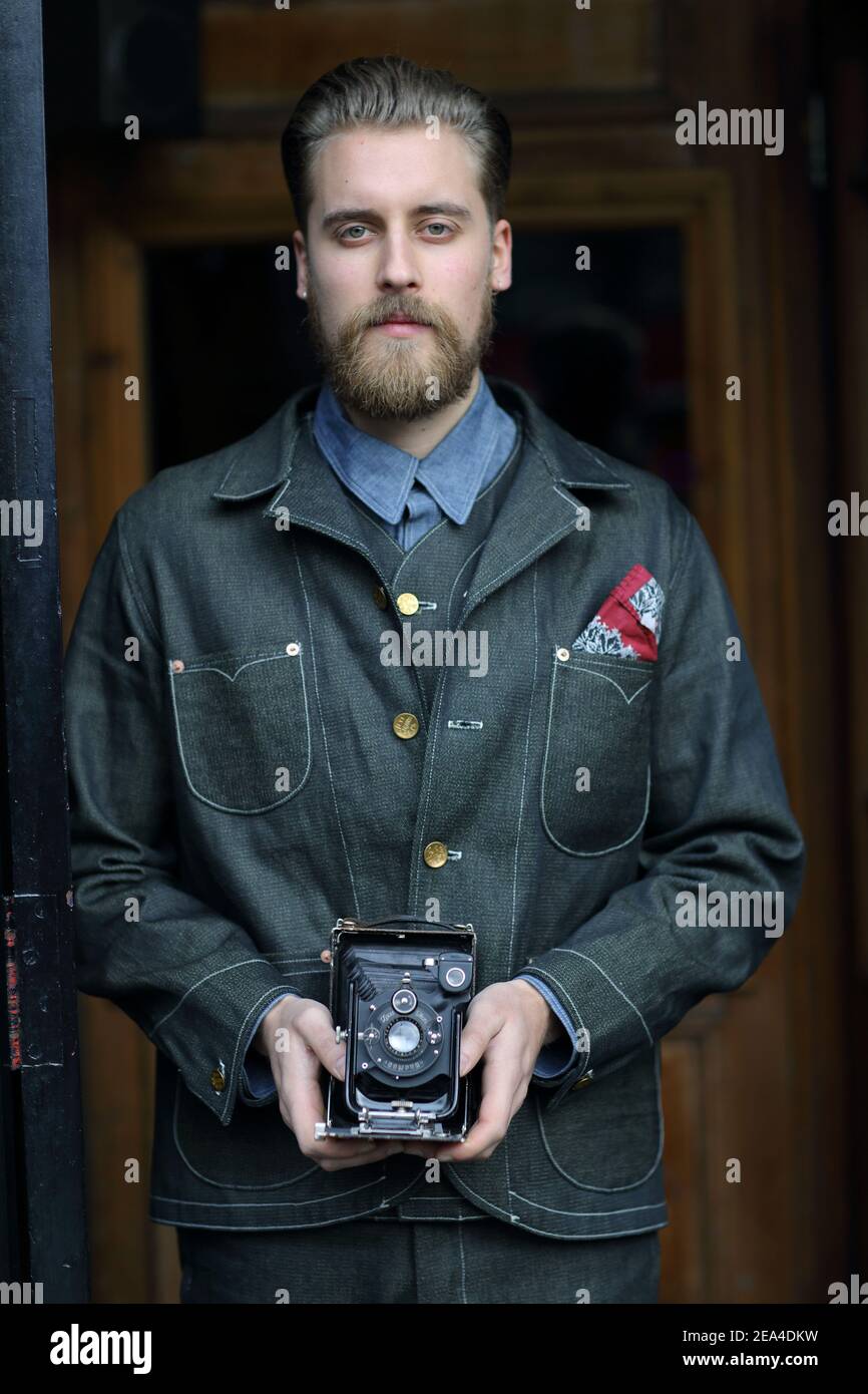 GRAN BRETAGNA / Inghilterra /Londra / giovane uomo che indossa jeans denim con fotocamera analogica d'epoca. Foto Stock