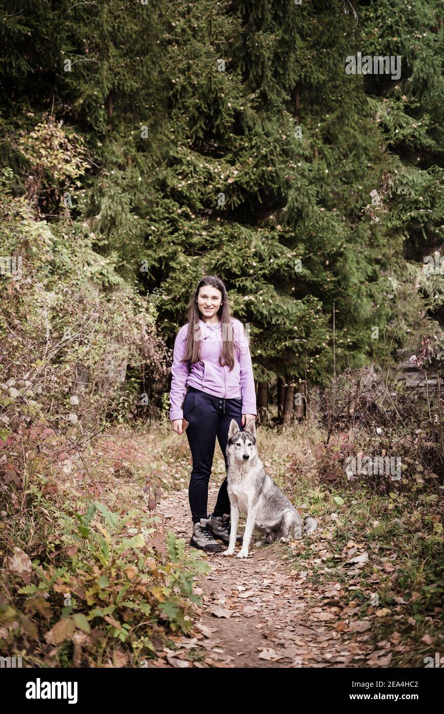 Ragazza che posa con un cane tipo lupo. Foto all'aperto Foto Stock