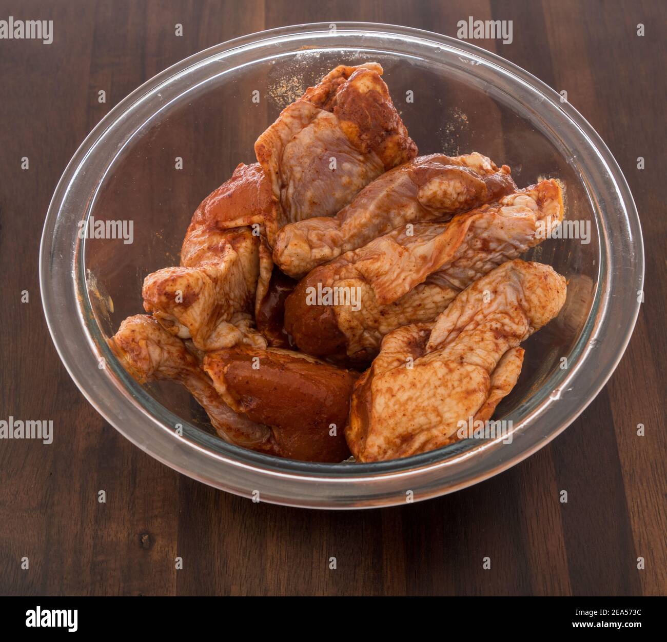 Ali di bufalo di pollo crude in ciotola con salsa di barbcue al miele aromatizzata su uno sfondo isolato. Foto Stock