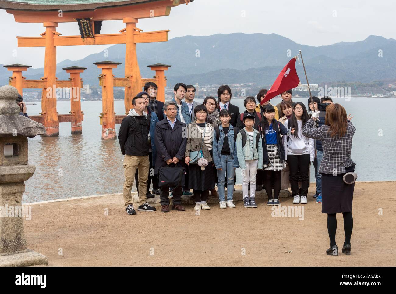 Il gruppo del tour ha una foto scattata dalla guida di fronte alla porta di Tori, l'isola di Miyamjima, Giappone Foto Stock