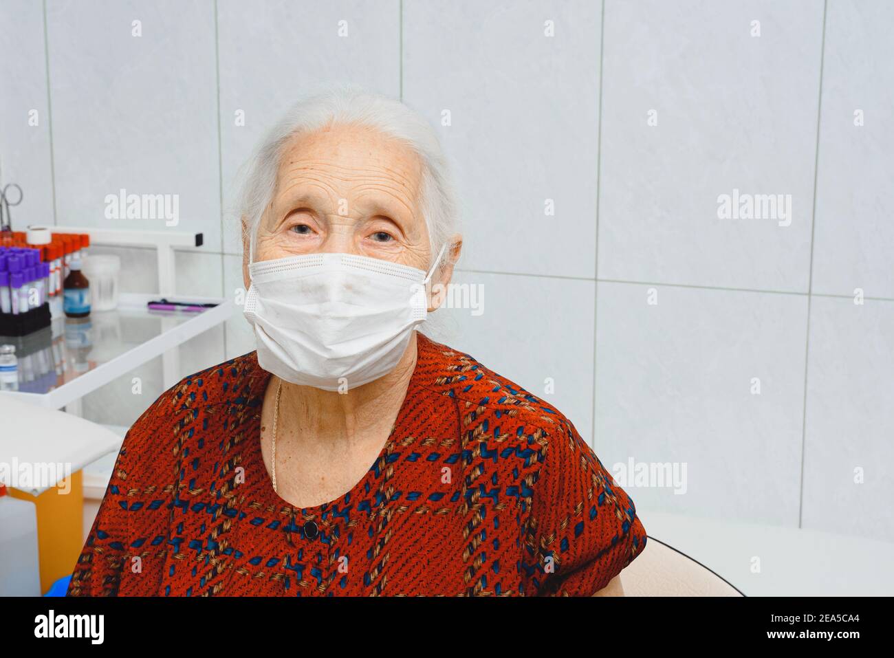 Ritratto di una donna anziana in una maschera medica. Donna anziana in un ufficio medico Foto Stock