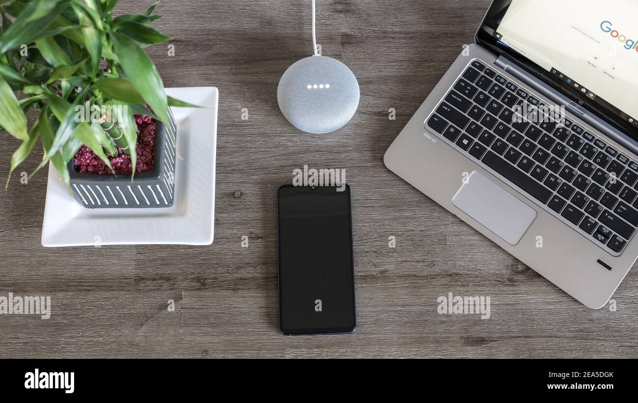 Adelaide, Australia - 7 luglio 2019: Google Home Mini con computer portatile HP con Windows 10 e telefono cellulare impostato sul tavolo accanto l'uno all'altro Foto Stock
