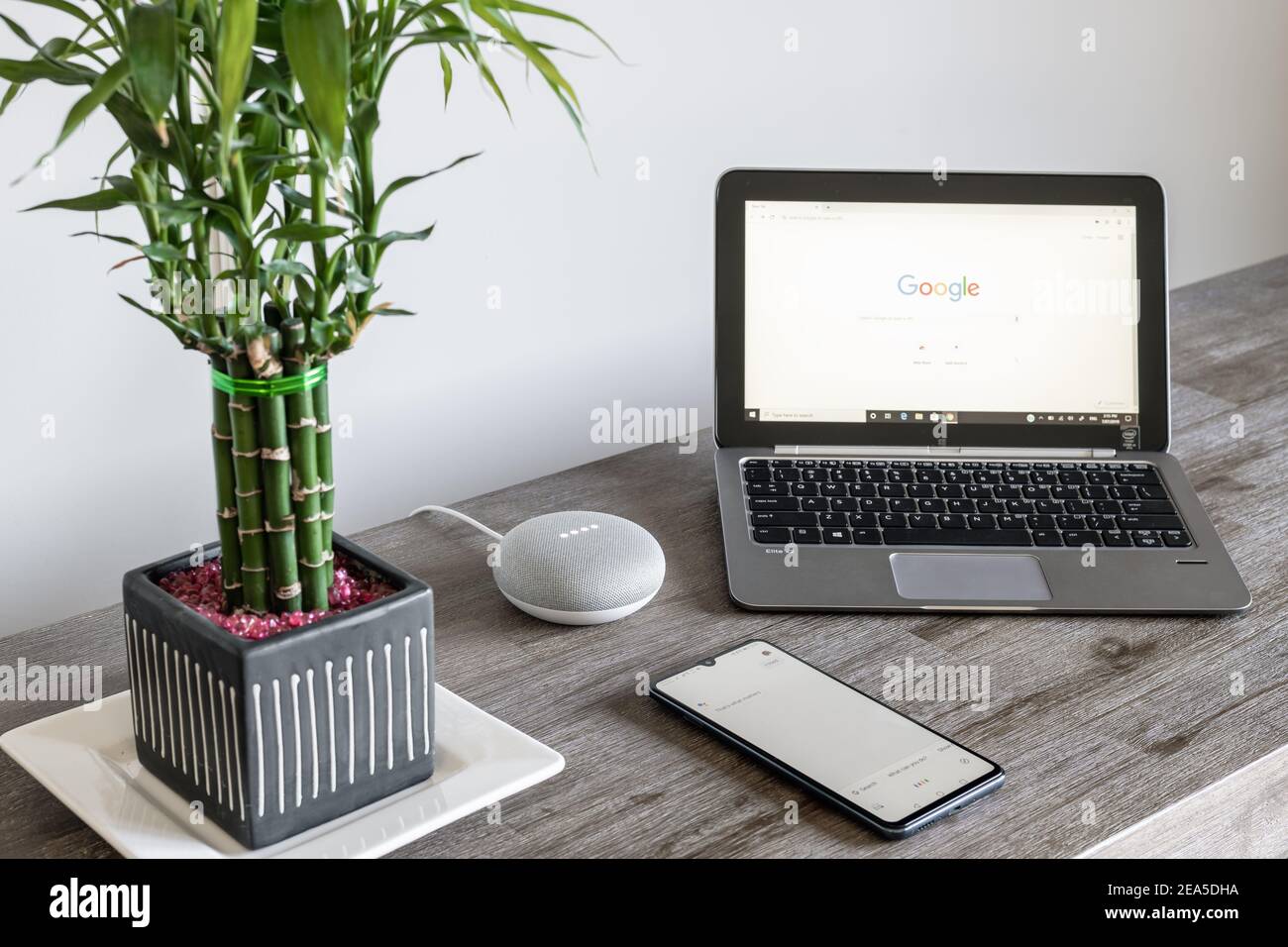 Adelaide, Australia - 7 luglio 2019: Google Home Mini con computer portatile HP con Windows 10 e telefono cellulare impostato sul tavolo accanto l'uno all'altro Foto Stock
