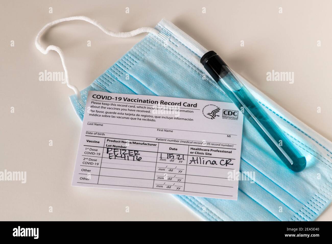 Pfizer Covid-19 scheda per la registrazione delle vaccinazioni con maschera e tubo per becher farmaceutico. Foto Stock