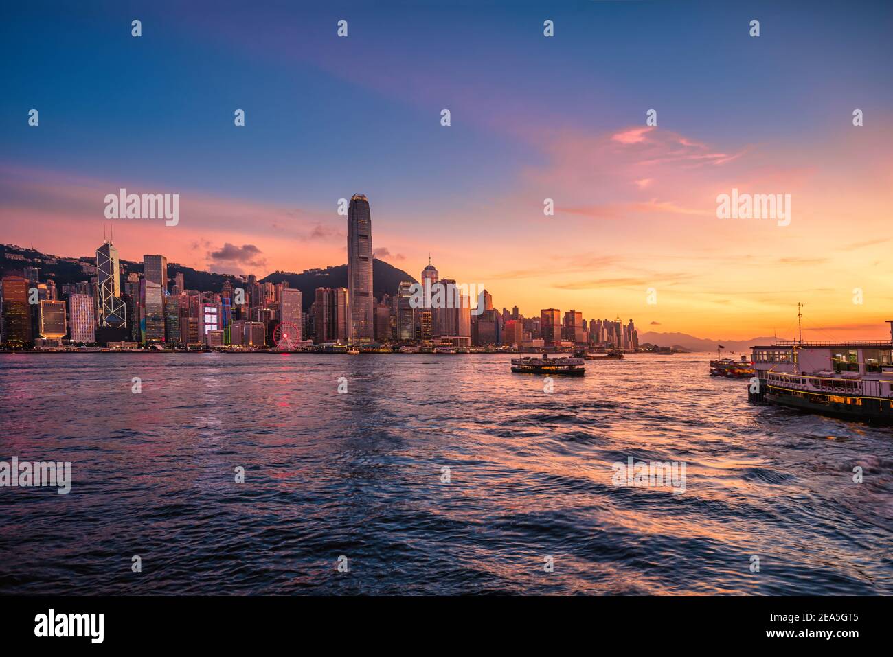 Skyline della città di Hong Kong al tramonto vista dal porto di Hong Kong. Foto Stock