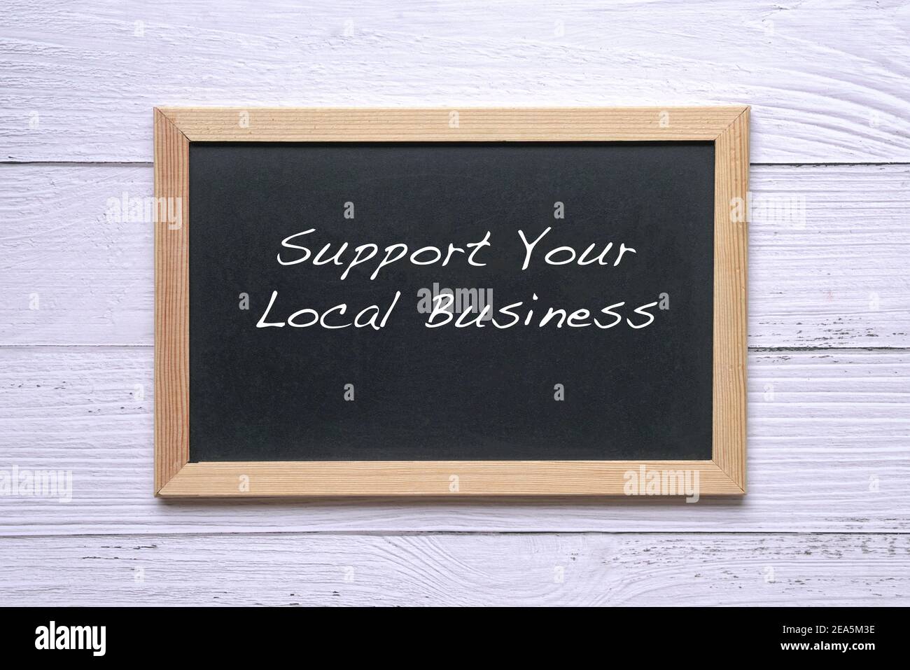 Sostenere il vostro commercio locale, parole scritte sulla lavagna. Promemoria per sostenere e acquistare beni e servizi nella tua comunità. Foto Stock