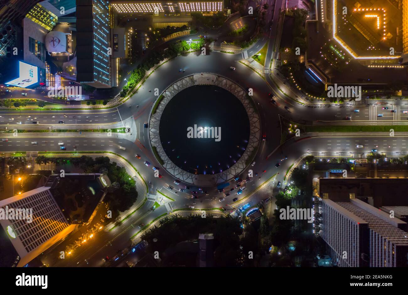 Vista aerea dall'alto del traffico di auto in movimento alla rotatoria del traffico stradale intorno al monumento Selamat Datang a Giacarta, Indonesia di notte Foto Stock