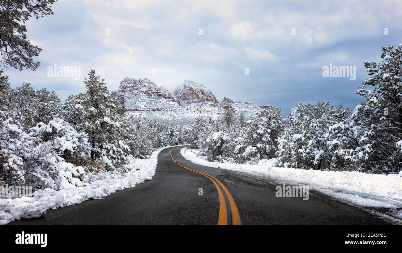 Paesaggio invernale panoramico con una strada tortuosa attraverso la neve sulle rocce rosse di Sedona, Arizona Foto Stock