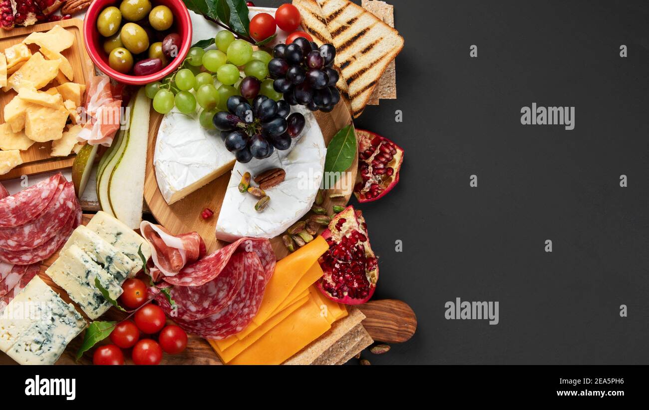 Tavola degli antipasti. Formaggio, fusit e cartone di carne su sfondo scuro. Vista dall'alto, spazio di copia Foto Stock