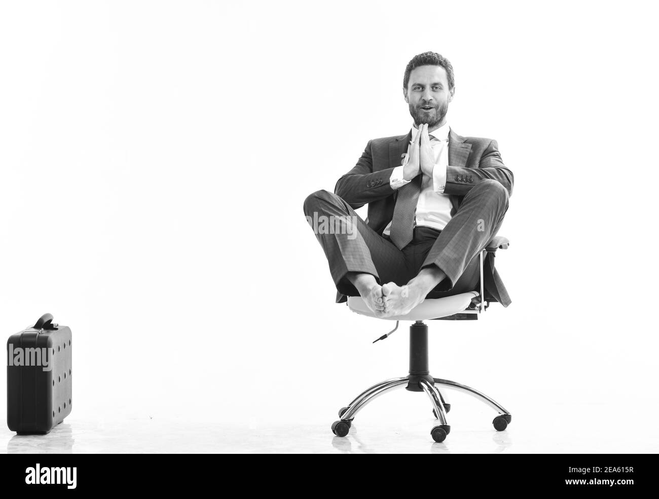 Rilassato bel giovane caucasico seduto e meditante sulla sedia da ufficio, isolato su sfondo bianco Foto Stock