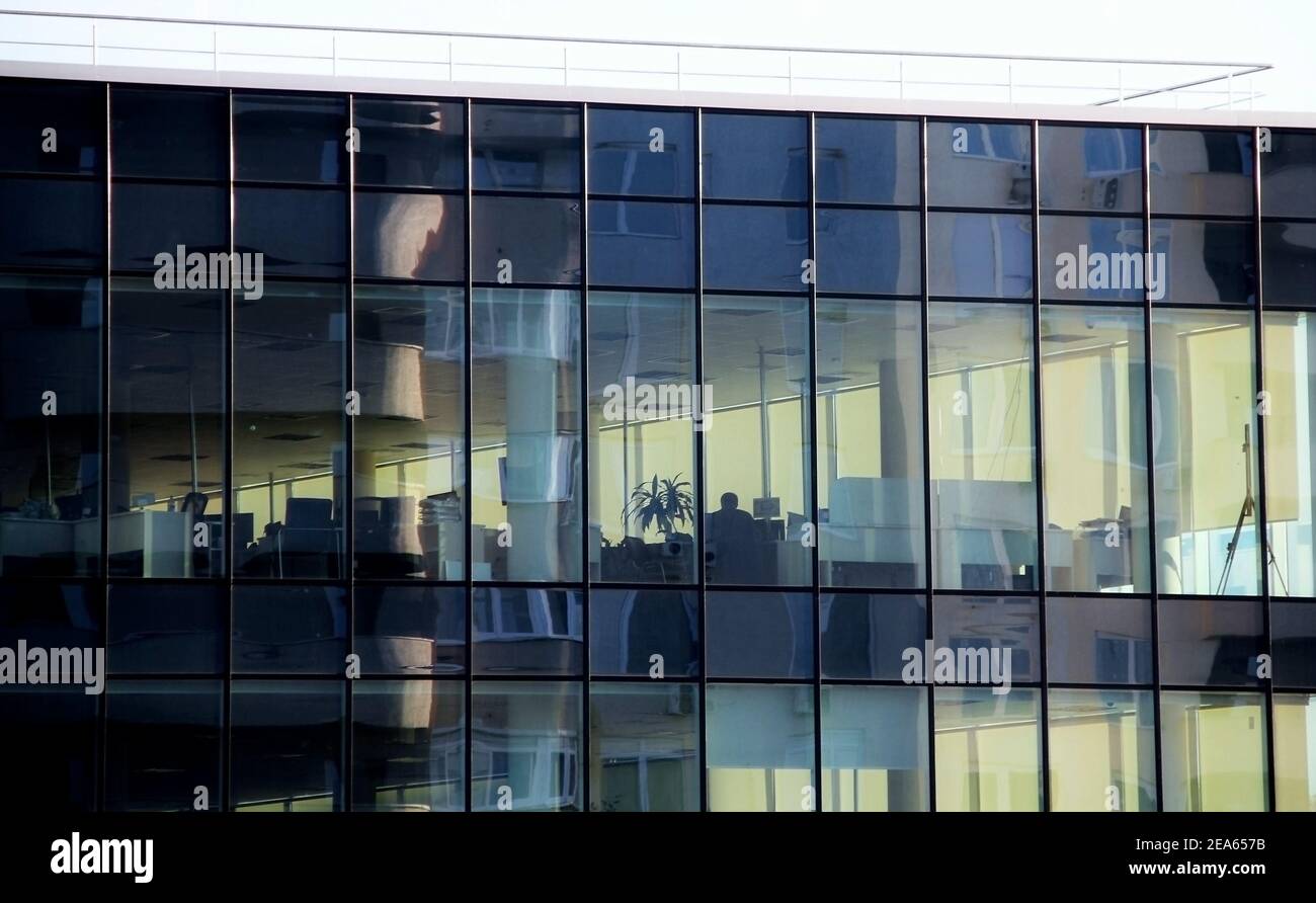 Parete di vetro di un moderno edificio per uffici con posti di lavoro vuoti Foto Stock