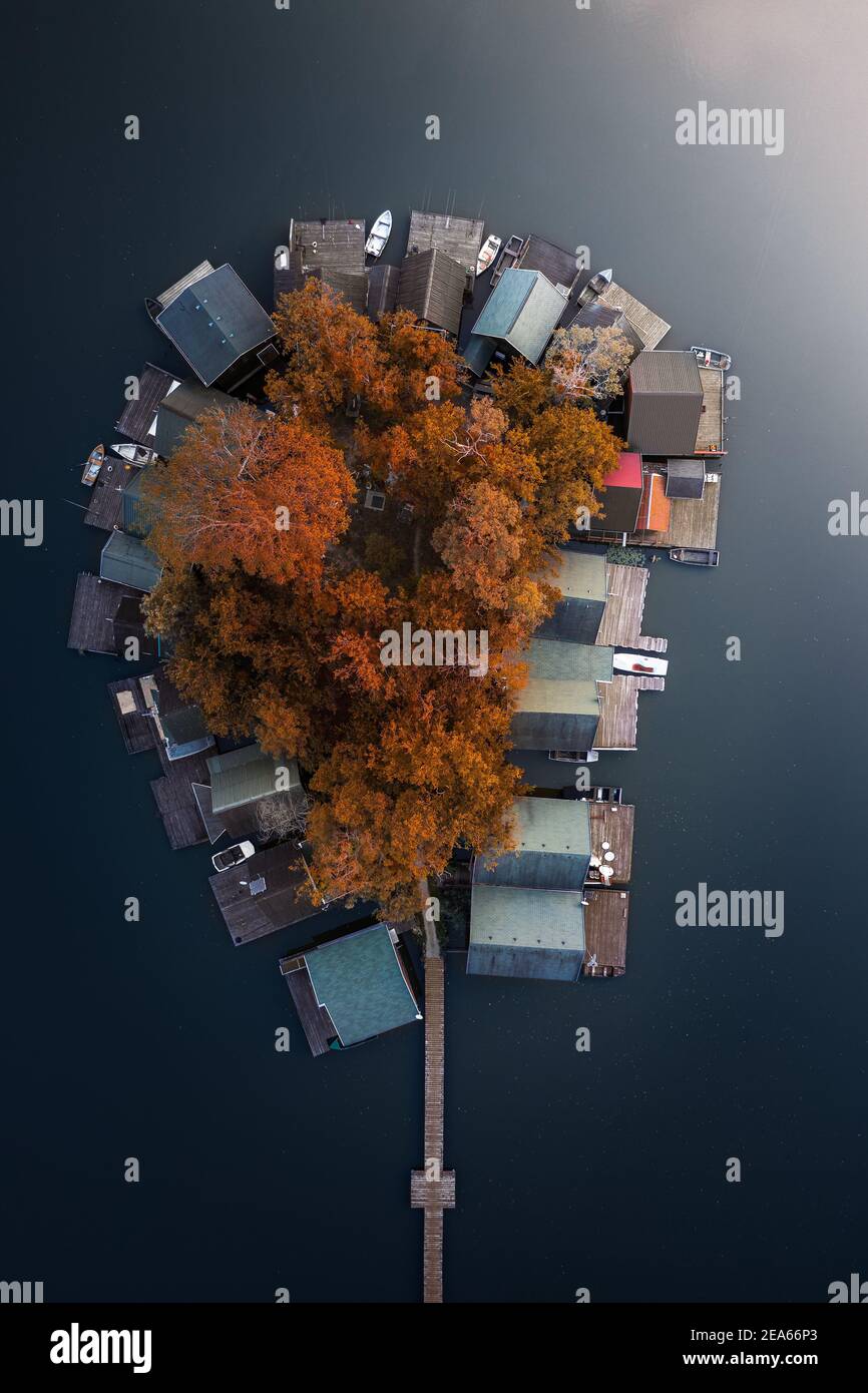 Tata, Ungheria - Vista aerea dall'alto verso il basso di una piccola isola di pescatori sul Lago Derito (Derito-to) con foglie autunnali e foglie al tramonto. Il lago può essere fo Foto Stock