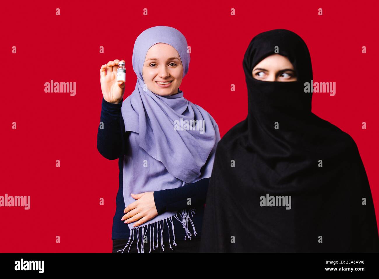 Giovani donne musulmane che indossano copricapo. Si sorride e contiene il  vaccino. Il secondo si affaccia lateralmente su uno sfondo rosso Foto stock  - Alamy