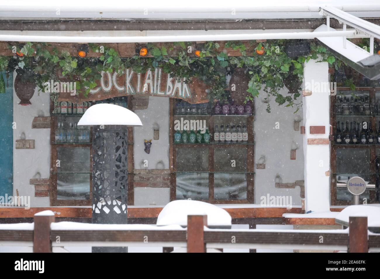 08 febbraio 2021, bassa Sassonia, Osnabrück: Decine di bottiglie di alcol si trovano sotto il cartello 'cocktail Bar' nella zona innevata all'aperto di un ristorante. Foto: Jonas Walzberg/dpa Foto Stock