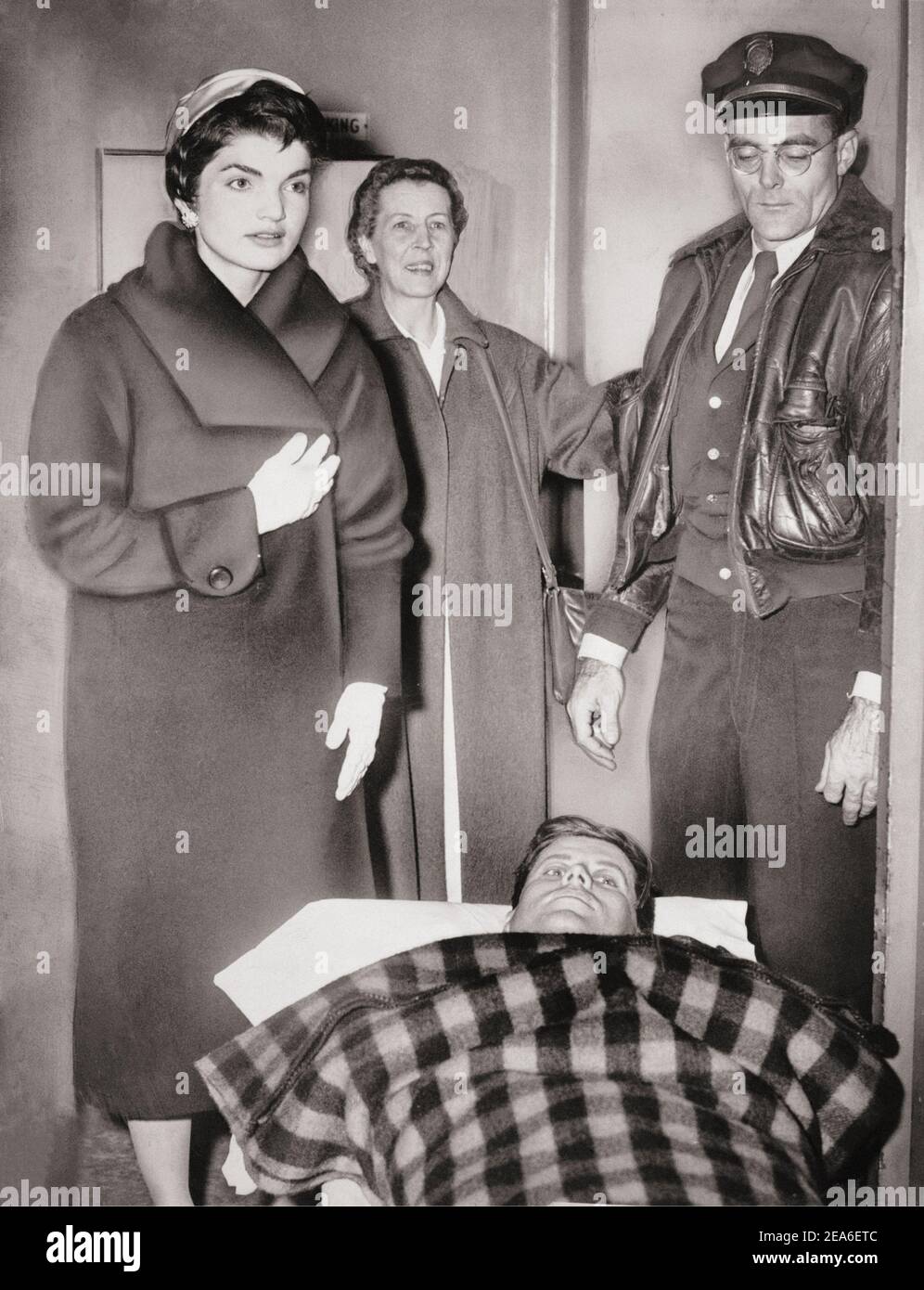 John F. Kennedy lascia il gurney dall'ospedale dopo la chirurgia spinale, come sua moglie Jacqueline si trova sopra di lui. STATI UNITI. 21 dicembre 1954 Foto Stock