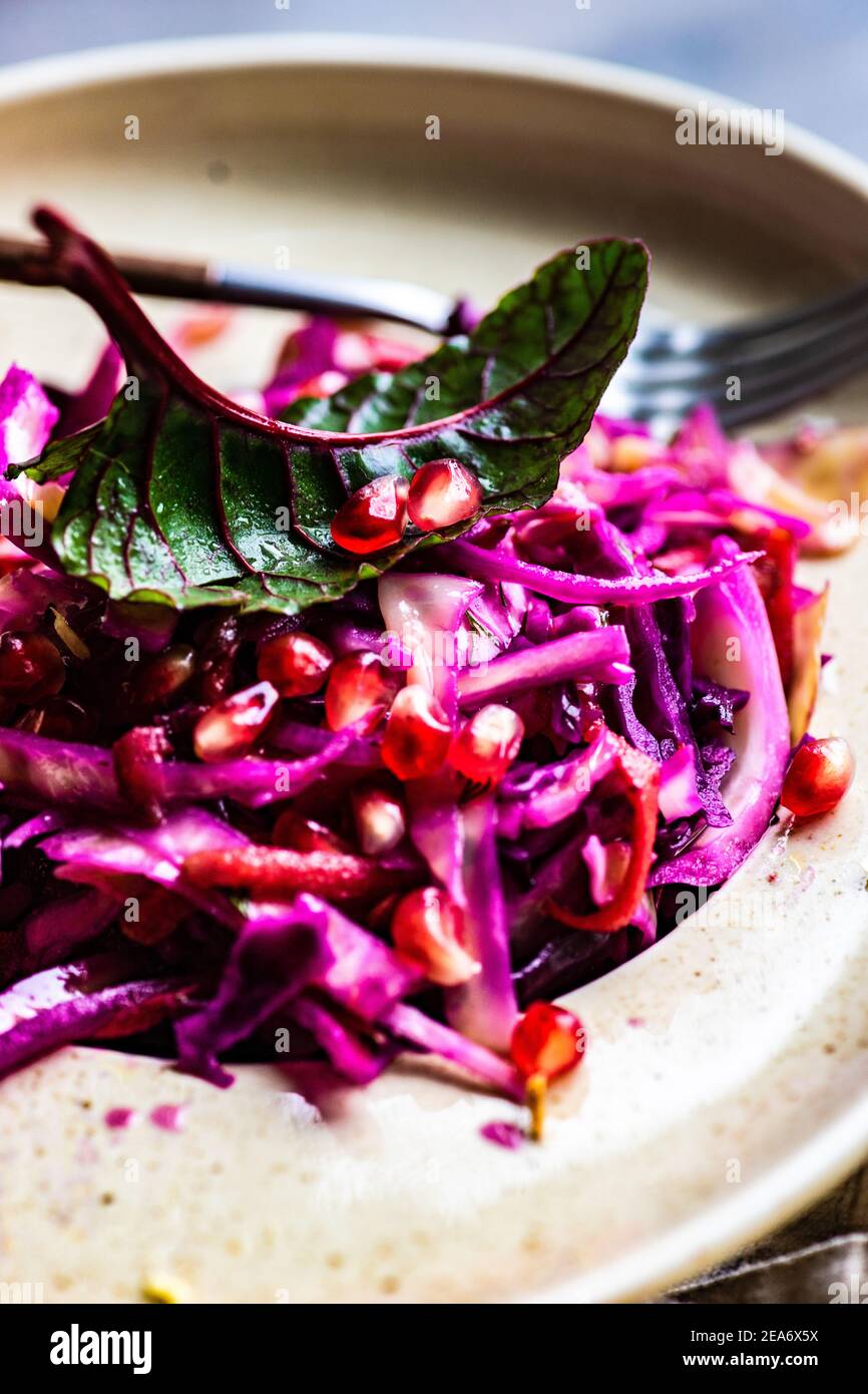 Insalata di cavolo rosso grattugiato con foglie di barbabietole e semi di melograno Foto Stock