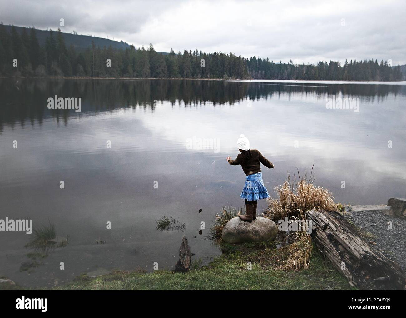 Ragazza che getta le rocce in un lago, Washington state, Stati Uniti Foto Stock