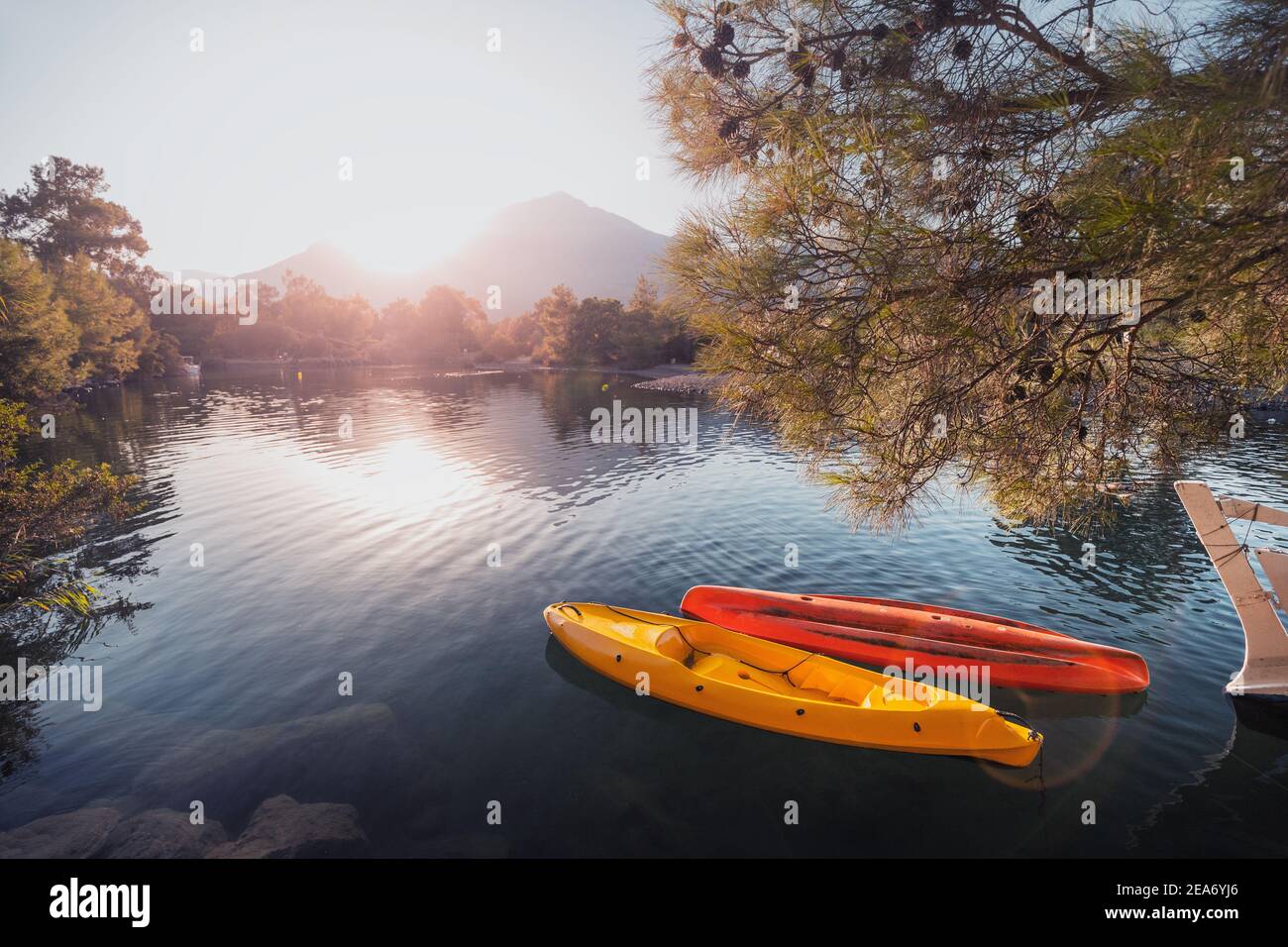 Due barche a remi, kayak senza persone, stanno saltando sulla onde ormeggiate verso la riva con una vista del il sole sorge sulla montagna Foto Stock
